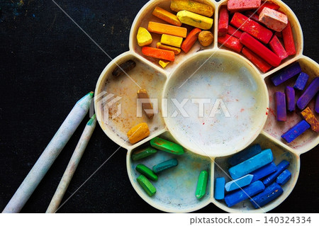 Top view of a rainbow palette with colorful pastel sticks and two blending tools placed on a dark surface, Top view of a rainbow palette with colorful pastel sticks and two blending tools placed on a dark surface, 140324334