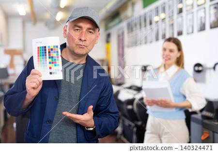 Service engineer demonstrating test page with color palette in his hand Service engineer demonstrating test page with color palette in his hand 140324471