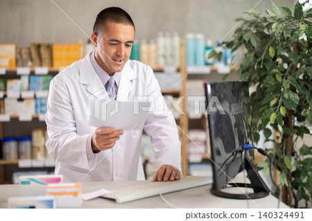 Man pharmacy employee works with computer Man pharmacy employee works with computer 140324491