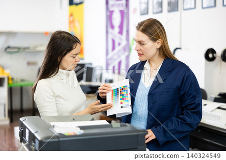 Two employees of printing house are discussing quality of plotter printing on color table Two employees of printing house are discussing quality of plotter printing on color table 140324549