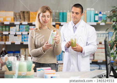 Young woman choosing shampoo while pharmacist offering in drugstore Young woman choosing shampoo while pharmacist offering in drugstore 140324553