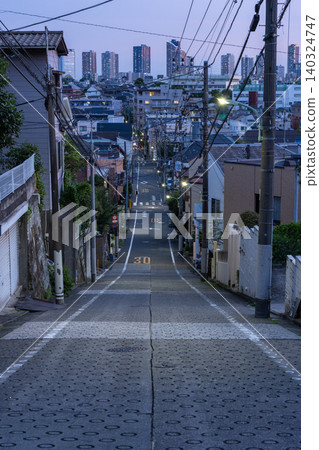 東京大田區東雪谷的一條傾斜的住宅街道,以及武藏小杉的塔樓公寓的夜景。 東京大田區東雪谷的一條傾斜的住宅街道,以及武藏小杉的塔樓公寓的夜景。 140324747