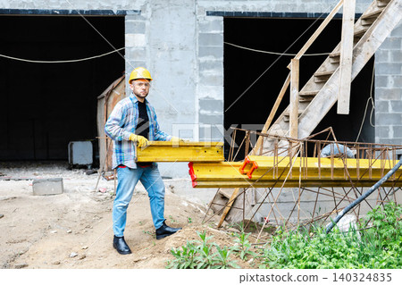 Construction worker carrying construction material on building site Construction worker carrying construction material on building site 140324835