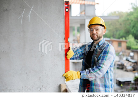 Construction worker checking level on concrete wall Construction worker checking level on concrete wall 140324837