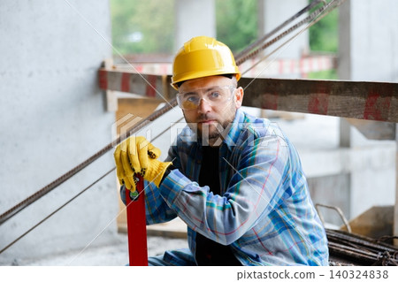 Construction worker resting holding spirit level on building site Construction worker resting holding spirit level on building site 140324838