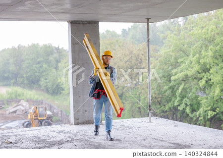 Construction worker carrying formwork beam on building site Construction worker carrying formwork beam on building site 140324844