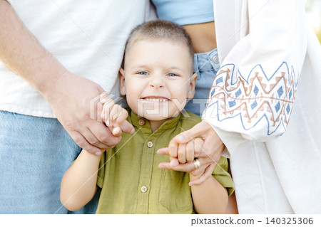 A Joyful Young Boy Smiling in a Family Portrait Captured on a Wooden Deck, Creating a Heartwarming and Timeless Scene A Joyful Young Boy Smiling in a Family Portrait Captured on a Wooden Deck, Creating a Heartwarming and Timeless Scene 140325306