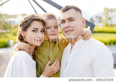 A Cheerful Family Posing for a Portrait Outside on a Sunny Summer Day, Capturing Precious Memories Together A Cheerful Family Posing for a Portrait Outside on a Sunny Summer Day, Capturing Precious Memories Together 140325309