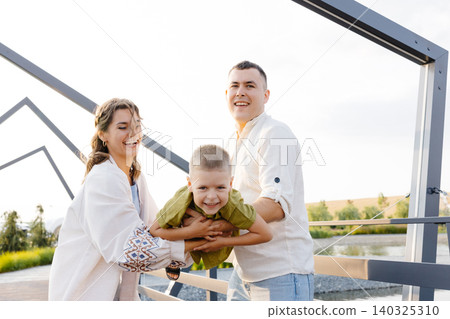 On a Beautiful Sunny Day, Parents Enjoy Lifting Their Child up in the Air, Creating Joyful Memories That Will Last a Lifetime On a Beautiful Sunny Day, Parents Enjoy Lifting Their Child up in the Air, Creating Joyful Memories That Will Last a Lifetime 140325310