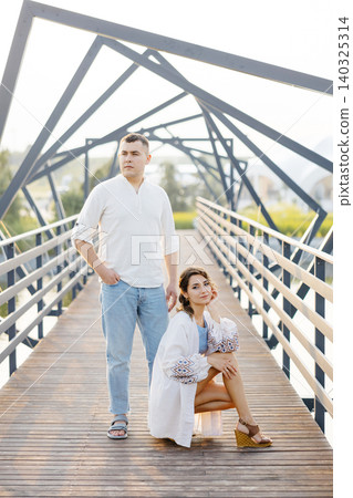 A Woman Leans on a Man's Shoulder as They Gaze Out Over the Railing of a Bridge, Lost in a Moment of Serene Contemplation 140325314