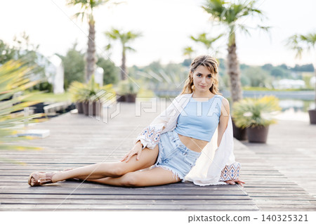 A Woman Relaxing Under a Palm Tree on a Secluded Dock, Surrounded by the Calming Sounds of the Water A Woman Relaxing Under a Palm Tree on a Secluded Dock, Surrounded by the Calming Sounds of the Water 140325321