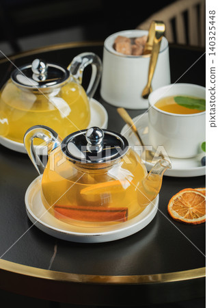 Fruit tea with mango and mint in a glass teapot on the table Fruit tea with mango and mint in a glass teapot on the table 140325448