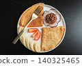A plate of crepes filled with chocolate spread and topped with banana slices and mint 140325465