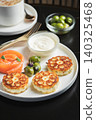 Savory Syrniki with Smoked Salmon, Olives and Sour Cream on White Plate 140325468