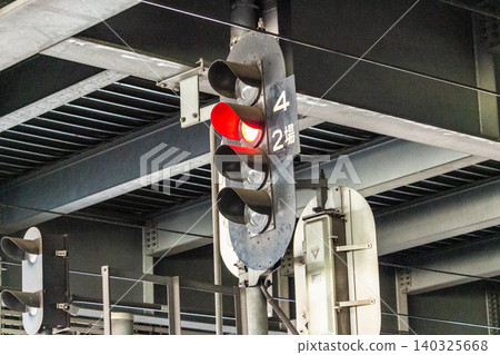 A four-light color light railway signal (station signal) and sign displaying a red light (stop indication). A four-light color light railway signal (station signal) and sign displaying a red light (stop indication). 140325668