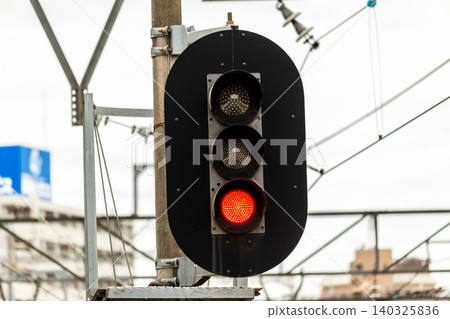 A three-light railway signal with a red light (stop indication) illuminated. 140325836