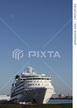 The cruise ship MITSUI OCEAN FUJI is anchored against a backdrop of a blue sky and the moon. 140326162