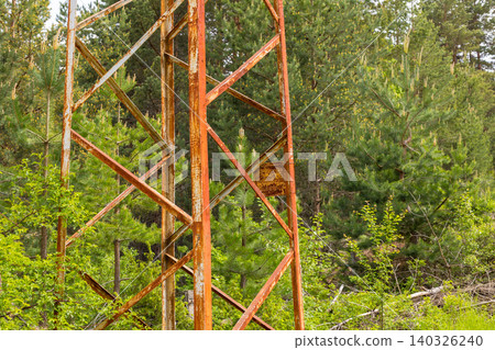 old rusty metal tower in a lush green pine forest old rusty metal tower in a lush green pine forest 140326240