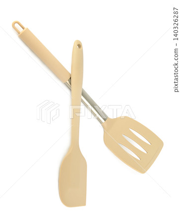 Crossed silicone kitchen spatula and slotted turner with handles isolated on clear white background Crossed silicone kitchen spatula and slotted turner with handles isolated on clear white background 140326287