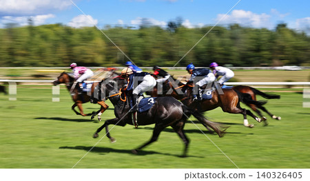Exciting horse race with jockeys competing at full speed on a racetrack. Dynamic sports action captured with motion blur, showcasing strength, speed, competition and equestrian performance. Exciting horse race with jockeys competing at full speed on a racetrack. Dynamic sports action captured with motion blur, showcasing strength, speed, competition and equestrian performance. 140326405