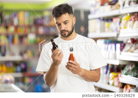 Middle-aged man choosing vegetable oil in supermarket Middle-aged man choosing vegetable oil in supermarket 140326829