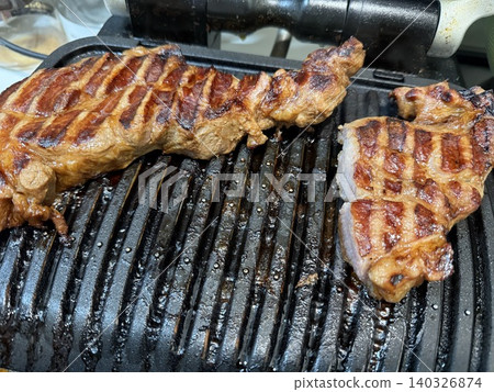 Grilled steak on stovetop grill with seared marks, ideal for barbecue concept background Grilled steak on stovetop grill with seared marks, ideal for barbecue concept background 140326874