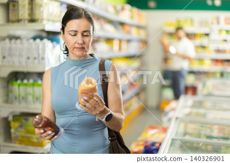 Middle-aged woman choosing vegetable oil in supermarket Middle-aged woman choosing vegetable oil in supermarket 140326901