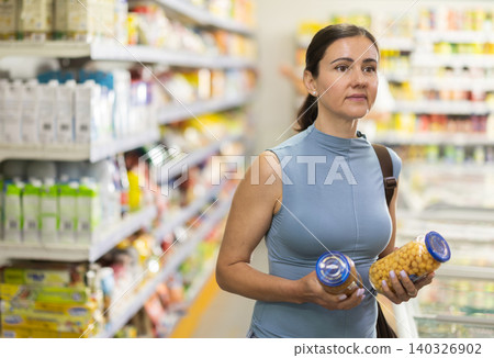 Buyer view assortment, woman choose canned beans Buyer view assortment, woman choose canned beans 140326902