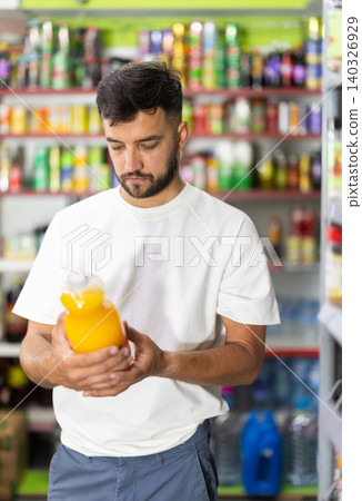 Man choosing soft drinks in grocery store, looking at products on shelves and reading labels on bottles 140326929