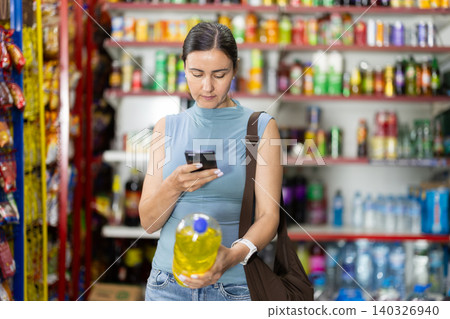 Woman get acquainted with non-alcoholic drink, scan QR code on label 140326940