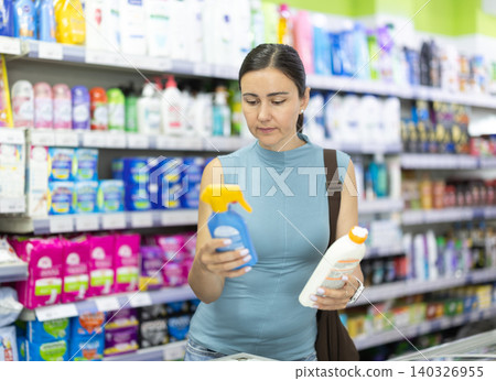 Adult woman buyer chooses sunscreen or tanning product in pharmacy in household goods department of supermarket Adult woman buyer chooses sunscreen or tanning product in pharmacy in household goods department of supermarket 140326955
