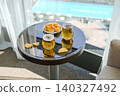 Two glasses of cold beer and potato chips on reflective table overlooking a resort pool. Bright sunny concept of travel, leisure and summer vacation relaxation in hotel room 140327492