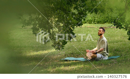 Man Meditating Outdoors Under Tree In Park 140327576