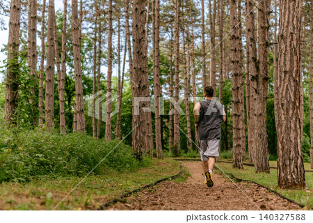 Male Runner Jogging through Pine Forest Trail 140327588