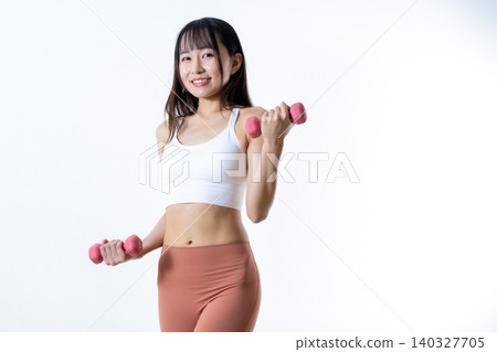A woman lifting dumbbells to work out; dumbbell curls; female strength trainer; angled shot; trimmed up. A woman lifting dumbbells to work out; dumbbell curls; female strength trainer; angled shot; trimmed up. 140327705