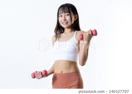 A woman lifting dumbbells to work out; dumbbell curls; female strength trainer; angled view; center trimmed up. A woman lifting dumbbells to work out; dumbbell curls; female strength trainer; angled view; center trimmed up. 140327707