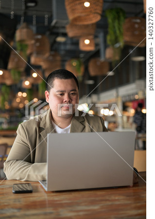 Focused plus size Isan Thai businessman using laptop at cafe vertical Focused plus size Isan Thai businessman using laptop at cafe vertical 140327760