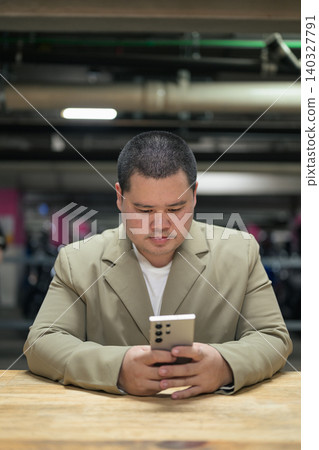 Focused plus size Isan Thai businessman using phone in garage vertical Focused plus size Isan Thai businessman using phone in garage vertical 140327791
