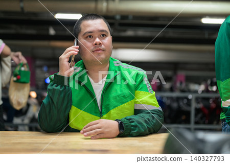 Thai delivery man from Isan talking on smartphone in parking garage Thai delivery man from Isan talking on smartphone in parking garage 140327793