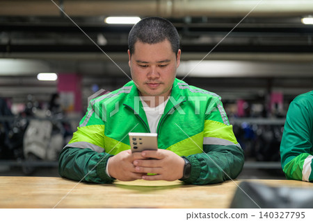 Thai delivery man from Isan using smartphone inside parking garage Thai delivery man from Isan using smartphone inside parking garage 140327795