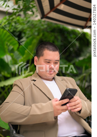 Focused plus size Isan Thai businessman using phone in garden vertical 140327884