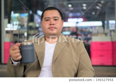 Plus size Thai businessman holding mug at night cafe horizontal Plus size Thai businessman holding mug at night cafe horizontal 140327958