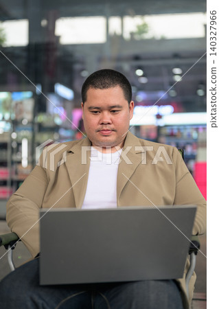 Plus size Isan Thai businessman using laptop computer at night cafe Plus size Isan Thai businessman using laptop computer at night cafe 140327966