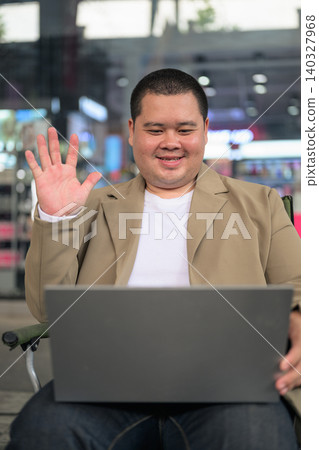 Smiling plus size Isan Thai businessman waving during laptop video call vertical shot Smiling plus size Isan Thai businessman waving during laptop video call vertical shot 140327968