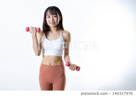 A woman smiling while working out at the gym; a picture of a woman who trains her muscles. A woman smiling while working out at the gym; a picture of a woman who trains her muscles. 140327976