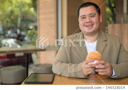 Plus size Isan Thai businessman smiling with burger at a restaurant Plus size Isan Thai businessman smiling with burger at a restaurant 140328014