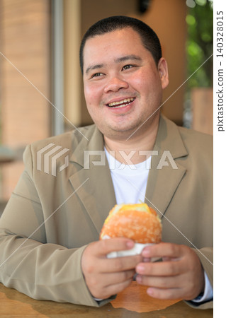 Plus size Isan Thai businessman laughing with burger at a restaurant 140328015