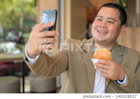 Plus size Isan Thai food influencer taking a selfie with a burger 140328017