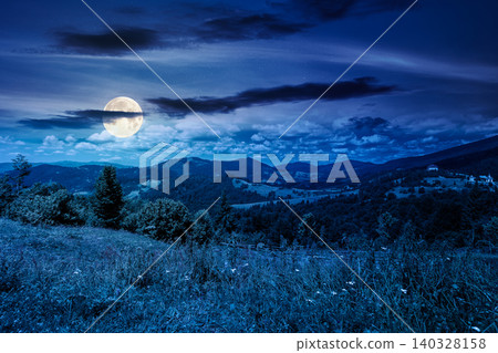 mysterious field on hillside in mountains near village at night. full moon over carpathian mountain landscape in summer. countryside view of alpine fields and rolling hills. cloudy sky 140328158