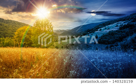 rural field on the hill. time change concept. view in to the valley at twilight. sun and moon over countryside mountain landscape. alpine pasture near forested hills. uncertainty and trust issues 140328159